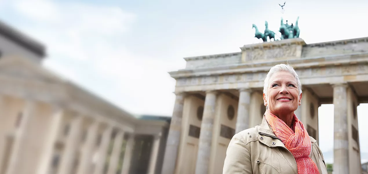 Ältere Frau lächelt vor dem Brandenburger Tor