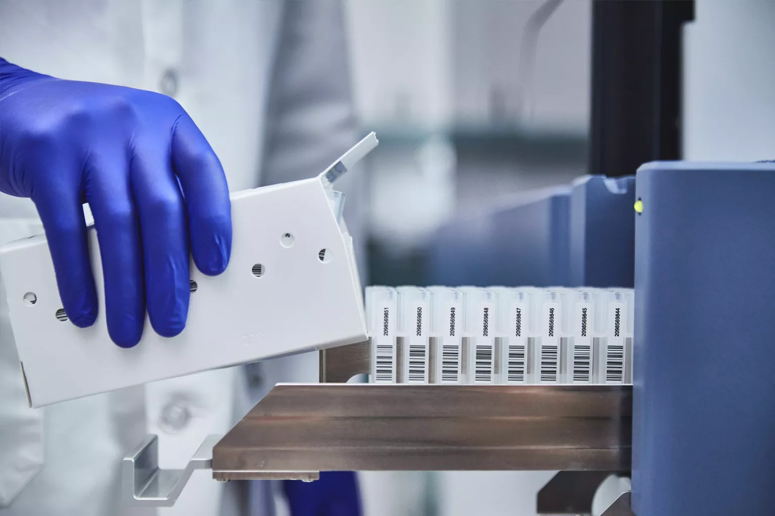 Labortechniker beim Laden von Probentrays in Laborumgebung.