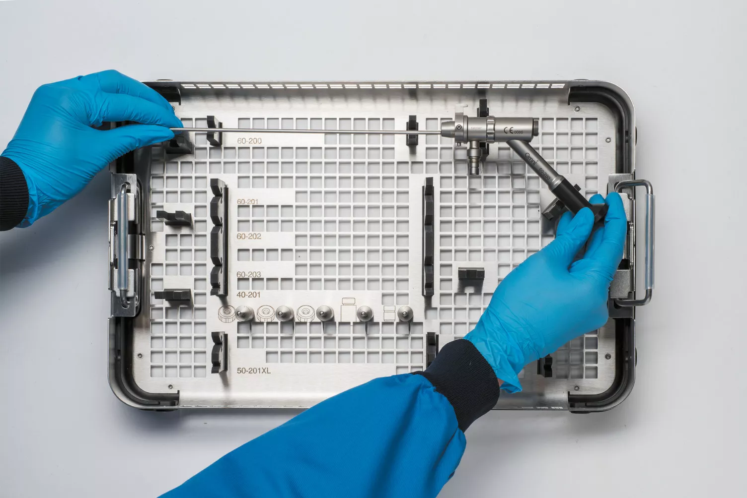 Behandschuhte Hand bei der Arbeit mit Instrumenten-Tray am Tisch.