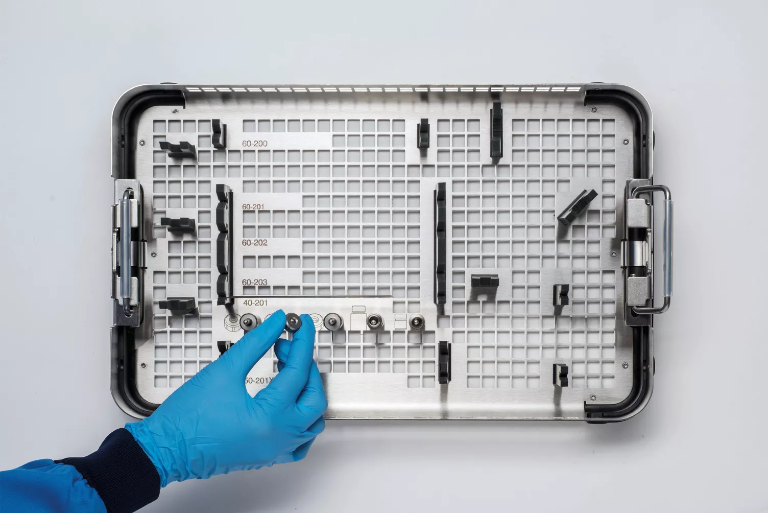 Behandschuhte Hand bei der Arbeit mit Instrumenten-Tray am Tisch.