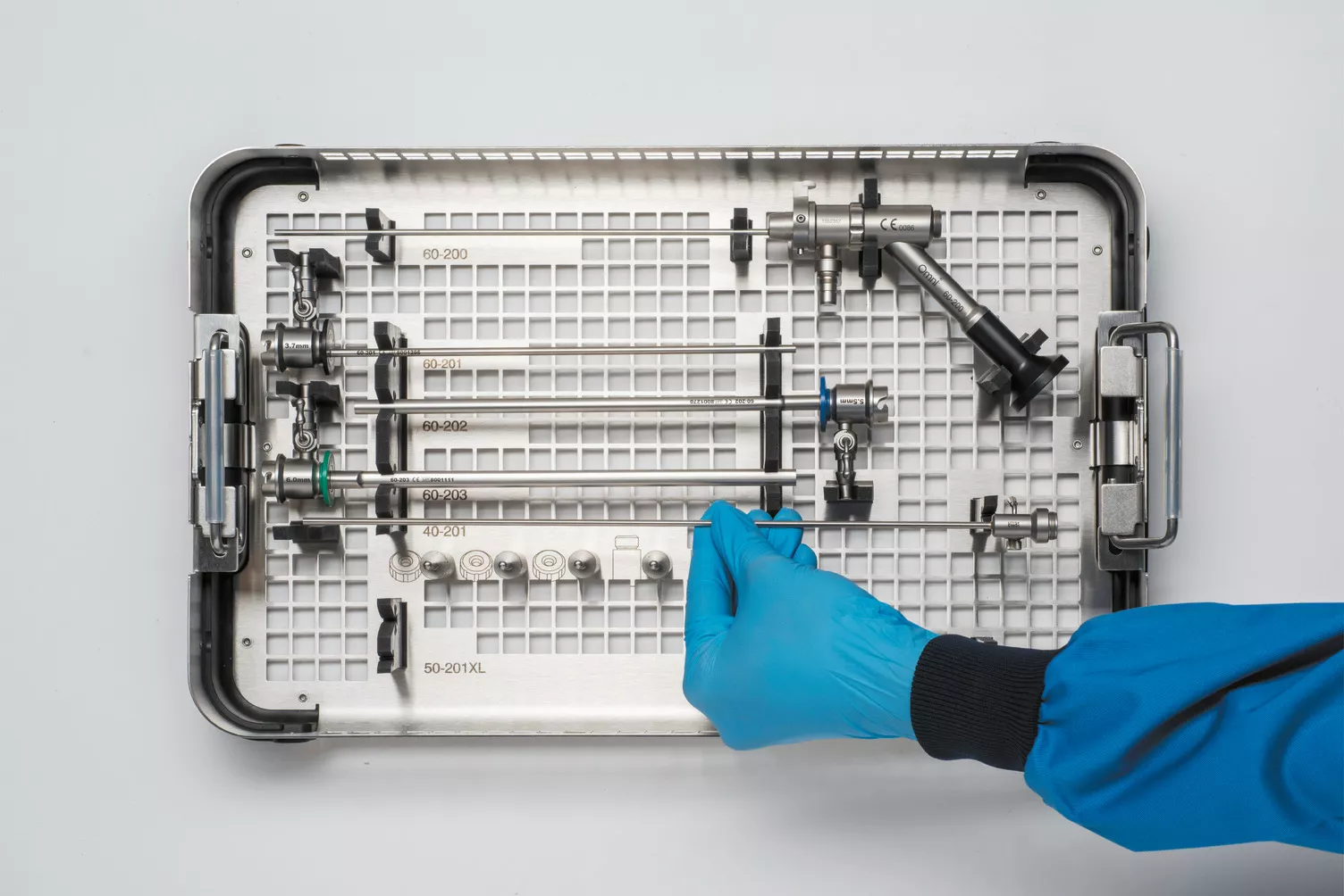 Behandschuhte Hand bei der Arbeit mit Instrumenten-Tray am Tisch.