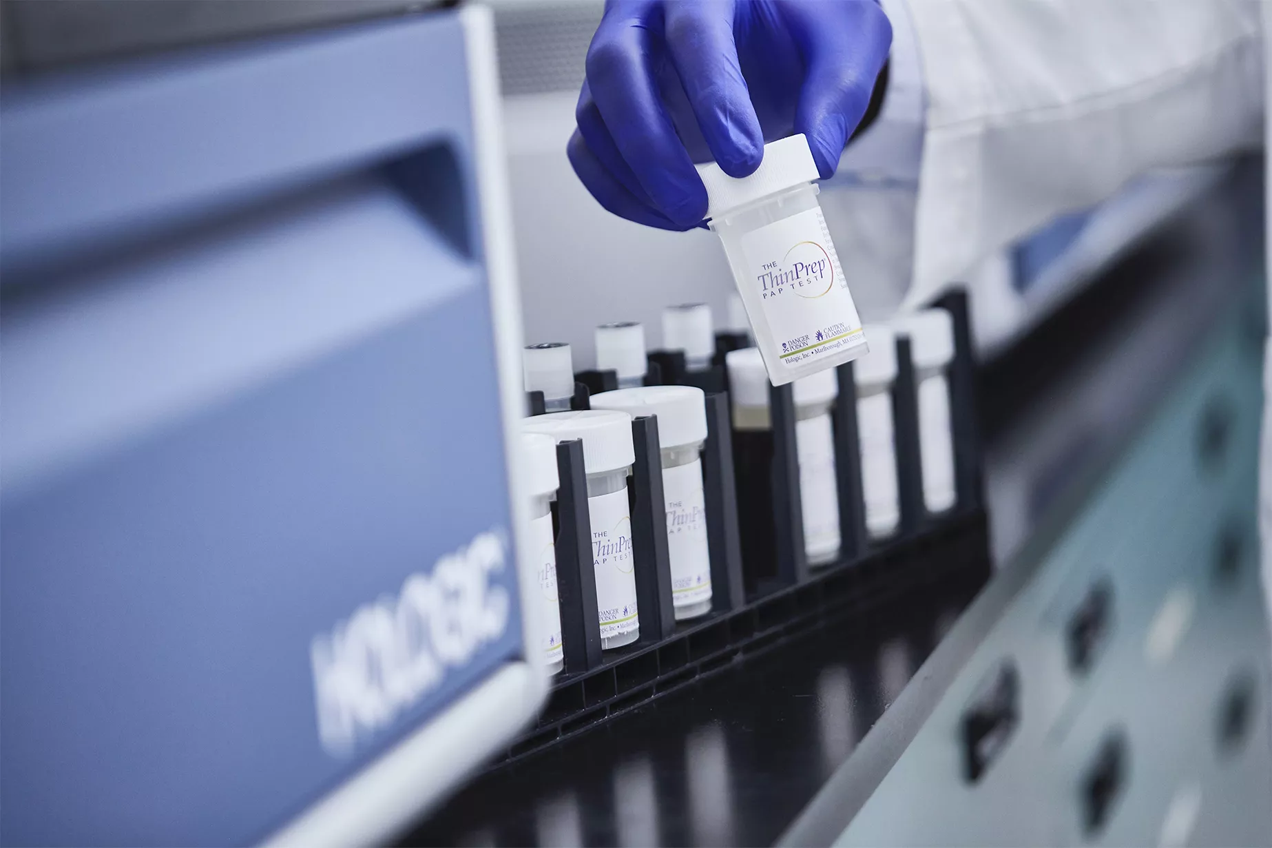 Hand mit Handschuh und Fläschchen